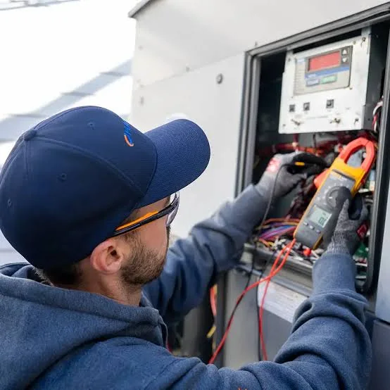 Technician testing HVAC electrical controls with a digital meter